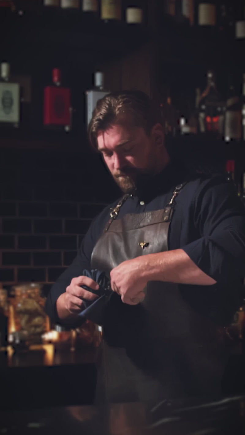 Bartender in a dark bar preparing a drink with focused concentration